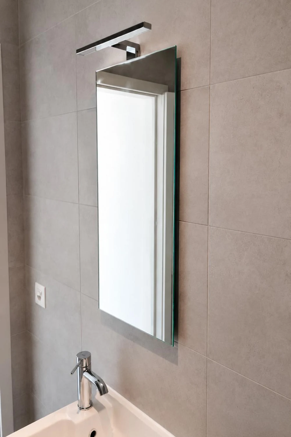 Lavabo d'angle surmonté d'un miroir et d'une applique