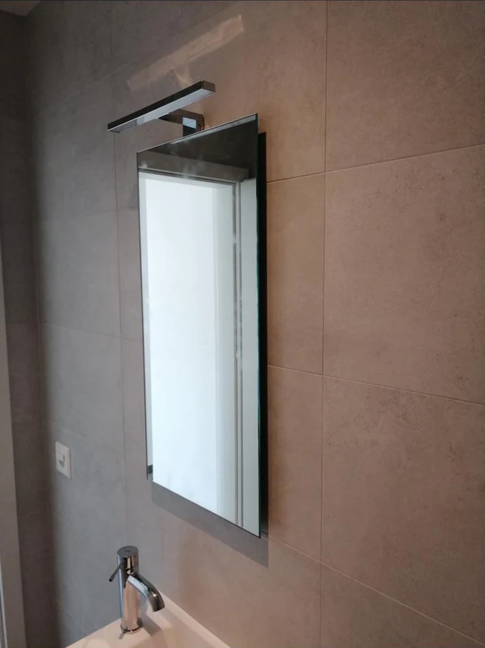 Lavabo et miroir sur un mur en carrelage grand format