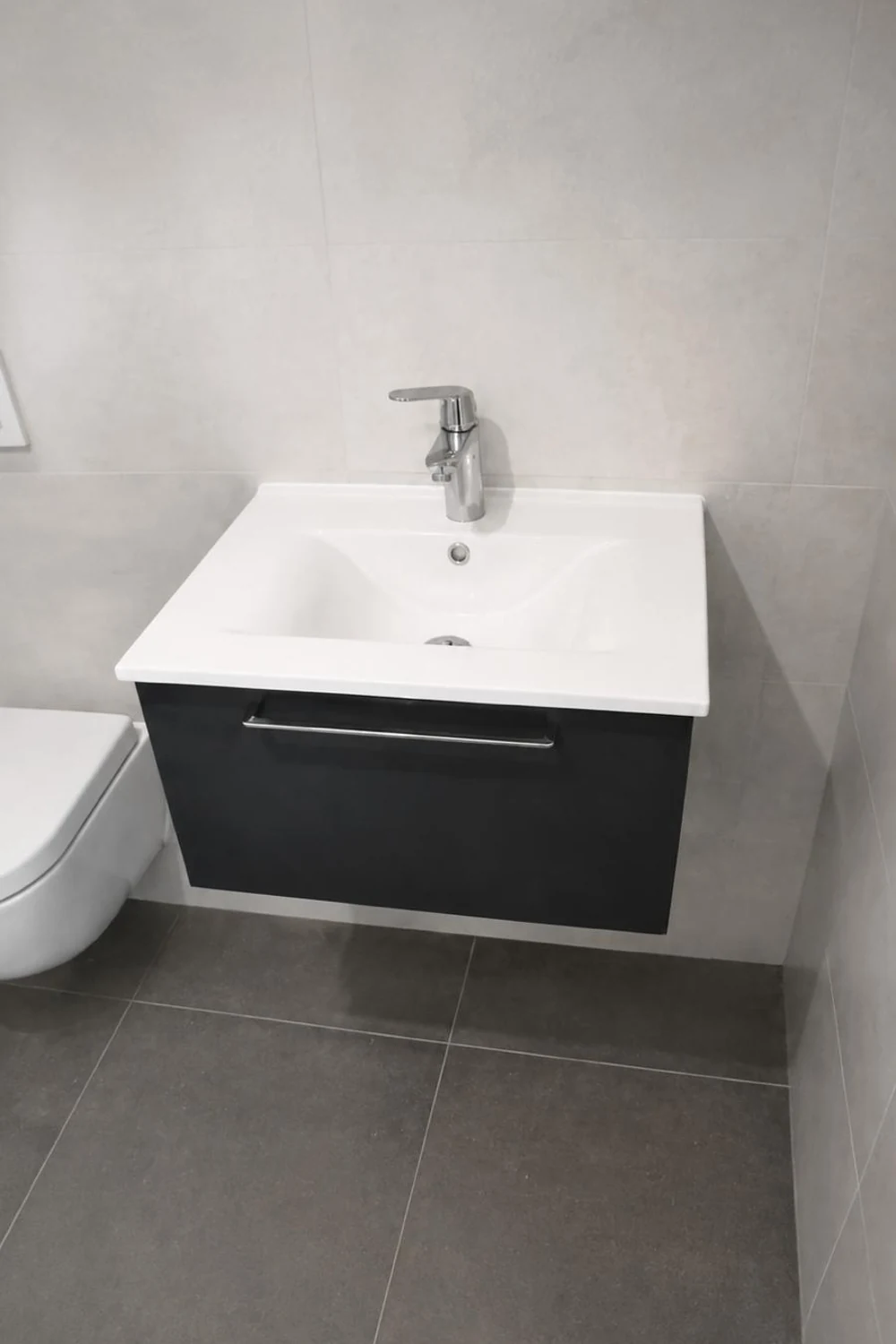 Meuble vasque suspendu foncé et WC suspendu, carrelage gris