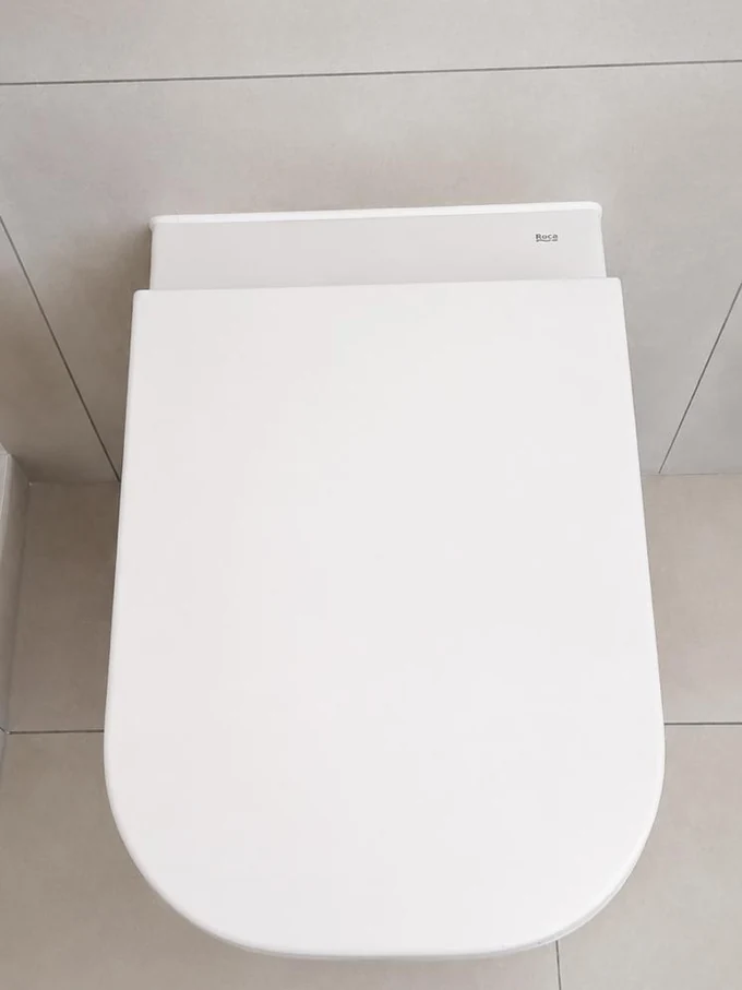 WC suspendu blanc posé contre un mur carrelé clair
